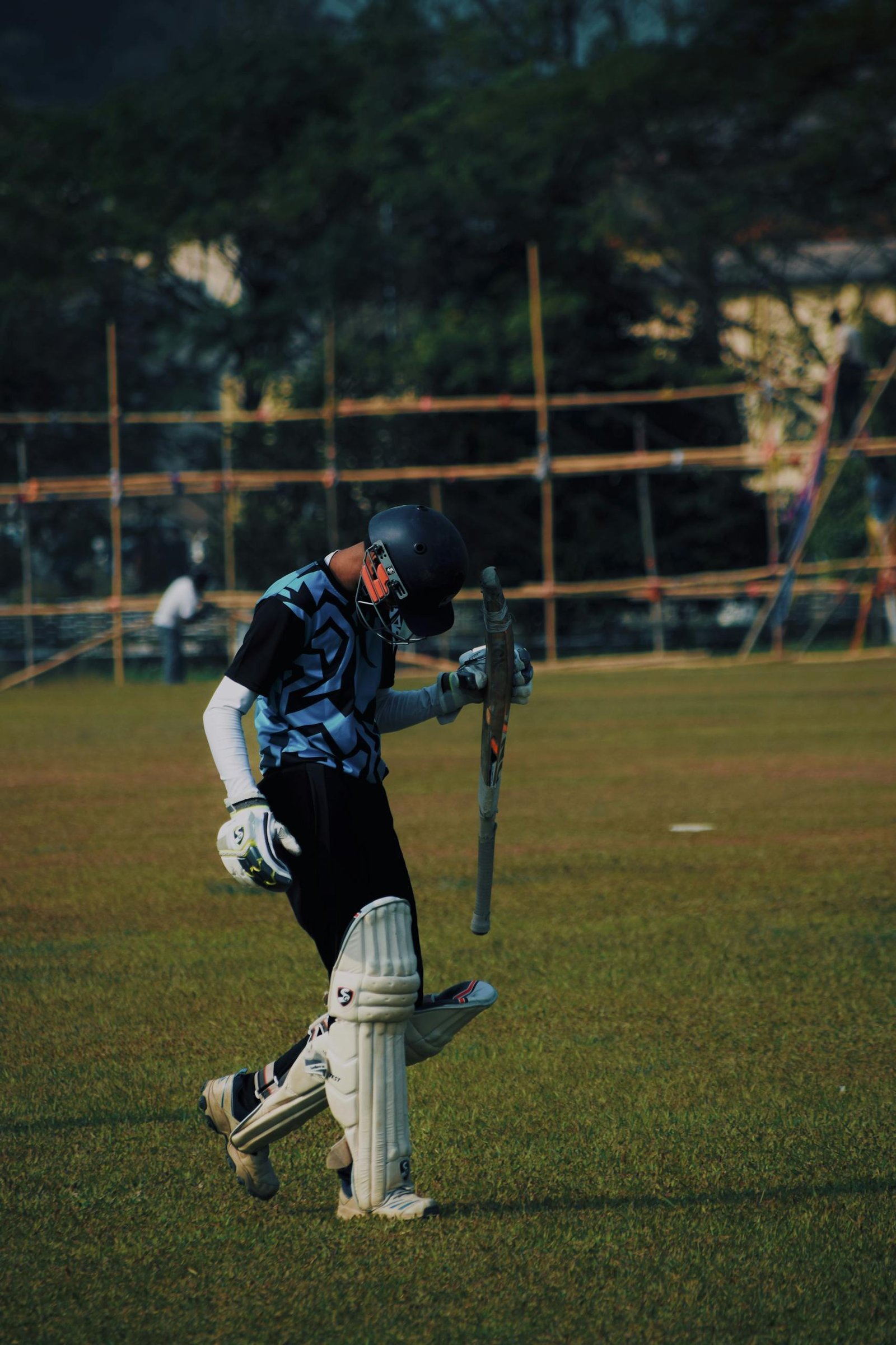 A cricketer in sportswear walking on a cricket field in Guwahati, India.
