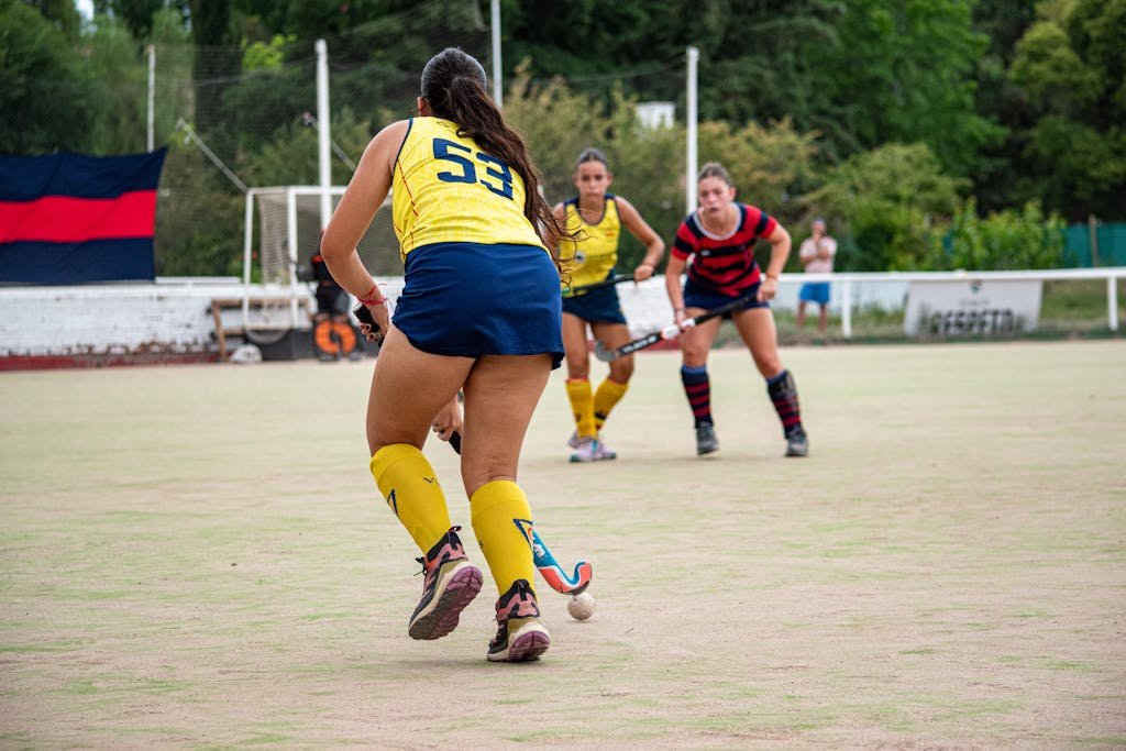 Field hockey players in action on outdoor turf during a competitive match.