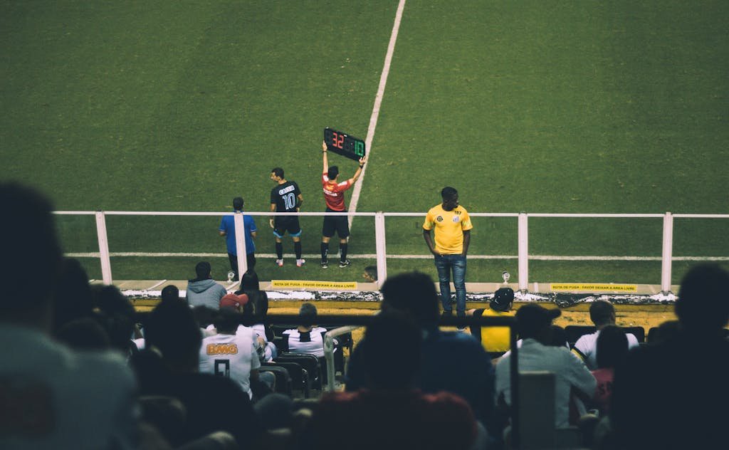 Soccer player substitution during a match at a stadium with an engaged audience.